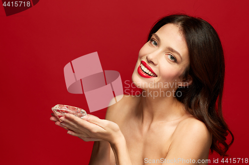 Image of beautiful woman with red lipstick holding diamond