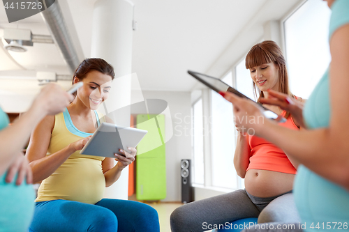 Image of happy pregnant women with tablet pc in gym