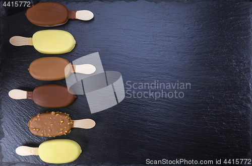 Image of Ice cream on stick covered with chocolate on black