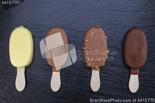 Image of Ice cream on stick covered with chocolate on black slate 