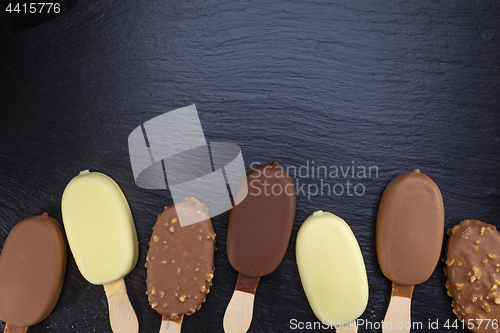 Image of Ice cream on stick covered with chocolate on black