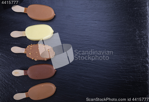 Image of Ice cream on stick covered with chocolate on black