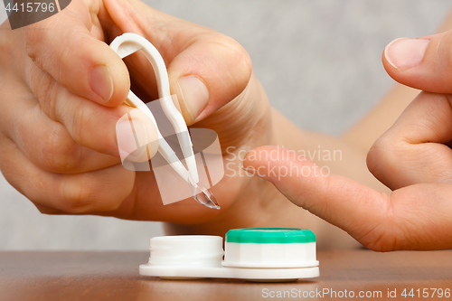 Image of woman hands putting on contact lenses