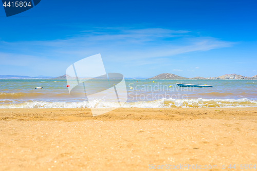 Image of European sandy beach, boat and blue sea.
