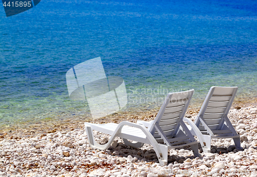 Image of Two deck chairs on beach in sunny summer day