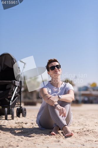 Image of Young mother with sunglasses relaxing on beach