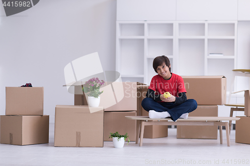 Image of boy sitting on the table with cardboard boxes around him