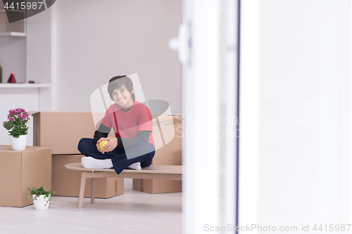 Image of boy sitting on the table with cardboard boxes around him