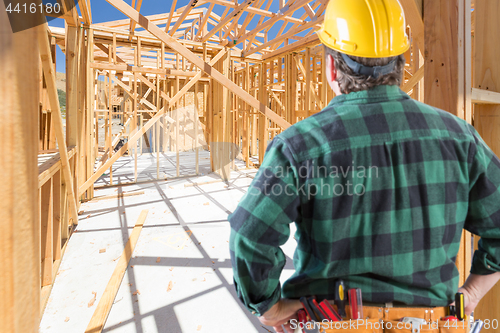 Image of Contractor Standing Inside Construction Framing of New House.