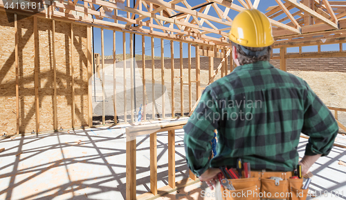 Image of Contractor Standing Inside Construction Framing of New House.