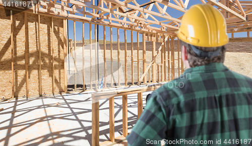 Image of Contractor Standing Inside Construction Framing of New House.