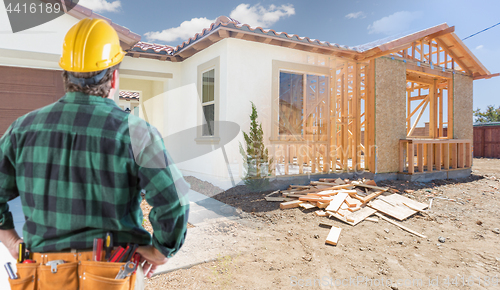 Image of Contractor Standing Outside Construction Framing and Photo of Ne