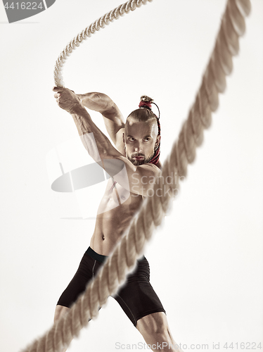 Image of Attractive muscular man working out with heavy ropes.