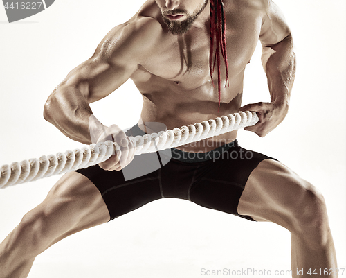 Image of Attractive muscular man working out with heavy ropes.