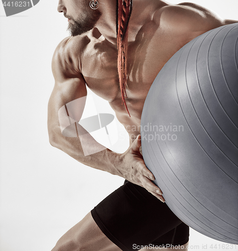 Image of Muscular man holding fitness ball, standing isolated on white