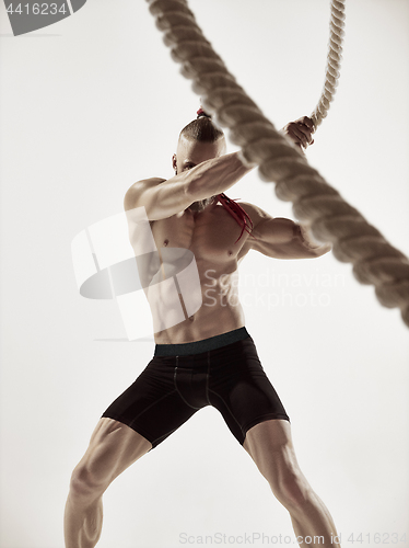 Image of Attractive muscular man working out with heavy ropes.