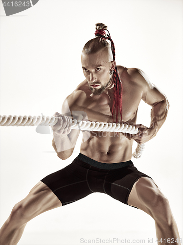 Image of Attractive muscular man working out with heavy ropes.