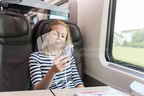 Image of Businesswoman communicating on mobile phone while traveling by train.