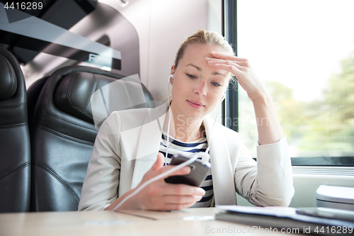 Image of Businesswoman communicating on mobile phone while traveling by train.