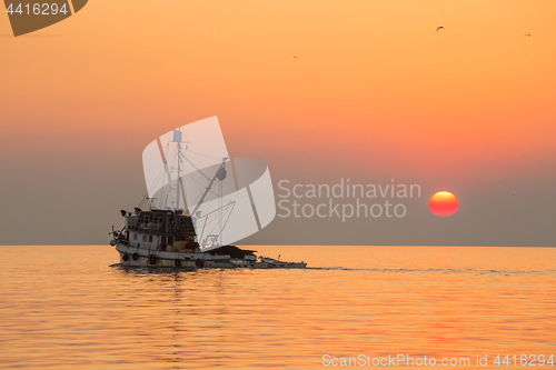 Image of Fishing boat sailing into sunset.
