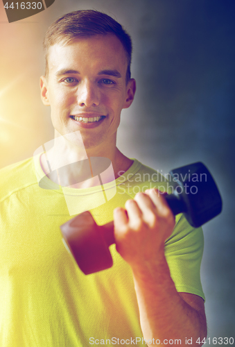 Image of smiling man with dumbbell in gym