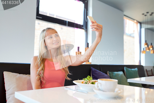 Image of woman with smartphone taking selfie at restaurant