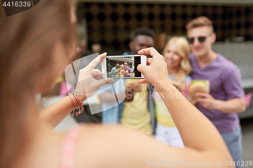 Image of woman photographing friends eating at food truck