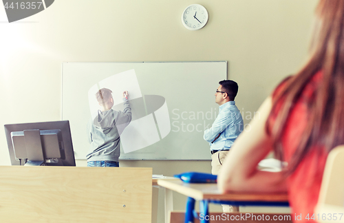 Image of teacher and student writing on board at school