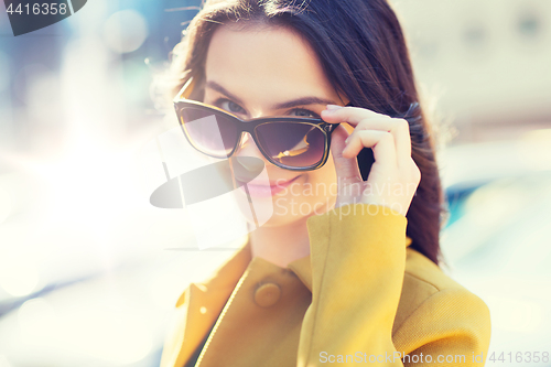 Image of smiling young woman with sunglasses in city