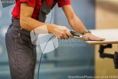 Image of worker with glue gun and board at workshop