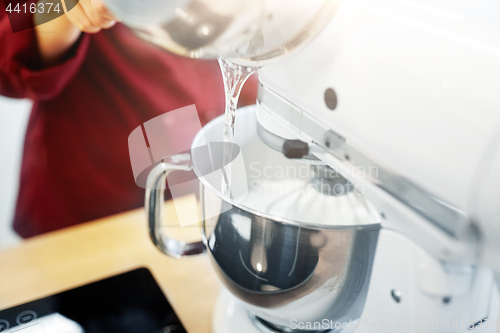 Image of chef pouring ingredient from pot into mixer bowl