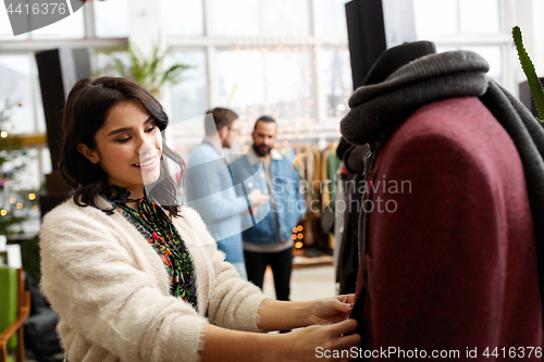 Image of happy woman choosing clothes at clothing store