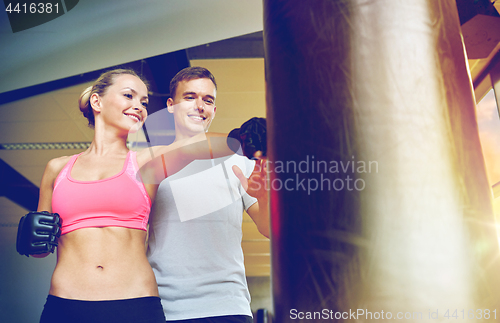 Image of smiling woman with personal trainer boxing in gym