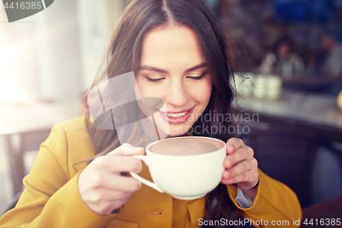 Image of happy woman drinking cocoa at city street cafe