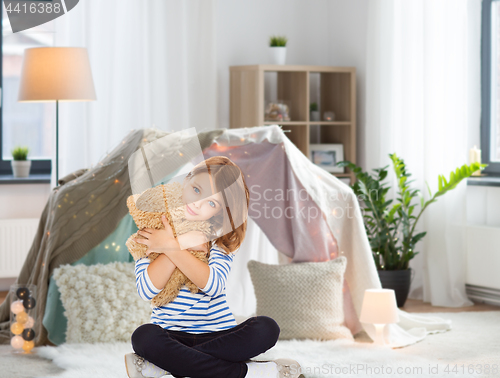 Image of cute little girl hugging teddy bear at home