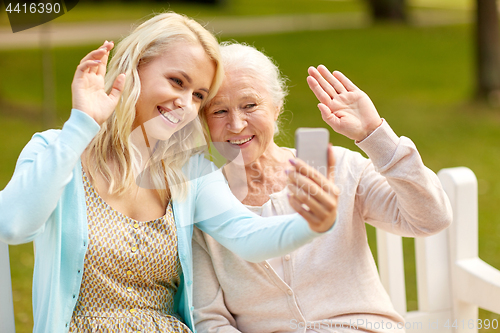 Image of daughter and senior mother taking selfie at park