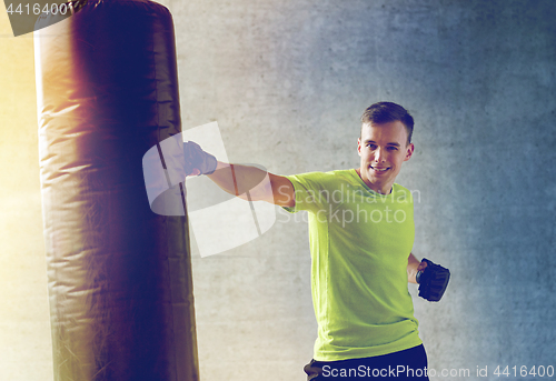 Image of young man in gloves boxing with punching bag