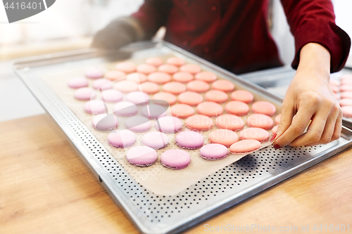 Image of chef with macarons on oven tray at confectionery