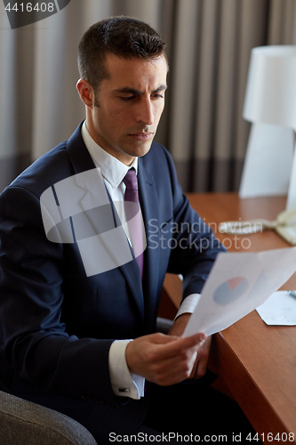Image of businessman with papers working at hotel room
