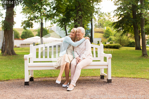 Image of daughter with senior mother hugging on park bench