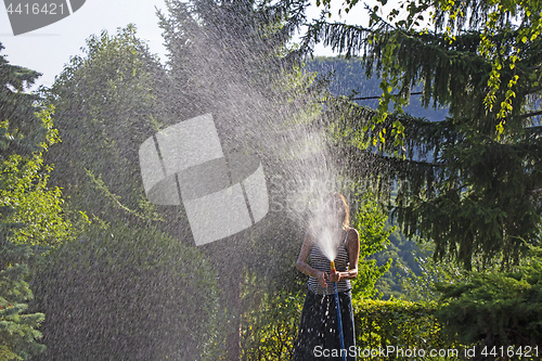 Image of A young woman Watering a lawn in the yard of the house, a backgr