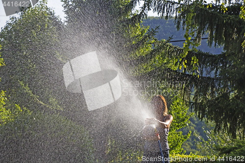 Image of A young woman Watering a lawn in the yard of the house, a backgr