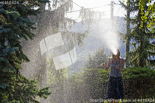 Image of A young woman Watering a lawn in the yard of the house, a backgr