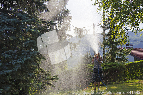 Image of A young woman Watering a lawn in the yard of the house, a backgr