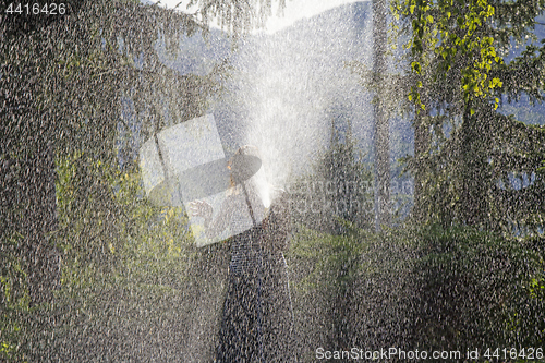 Image of A young woman Watering a lawn in the yard of the house, a backgr