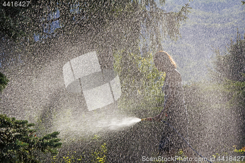 Image of A young woman Watering a lawn in the yard of the house, a backgr