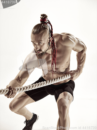 Image of Attractive muscular man working out with heavy ropes.