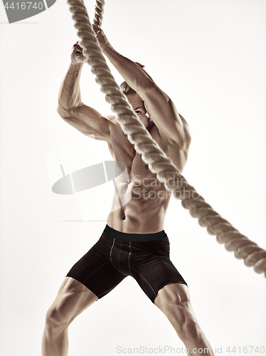 Image of Attractive muscular man working out with heavy ropes.