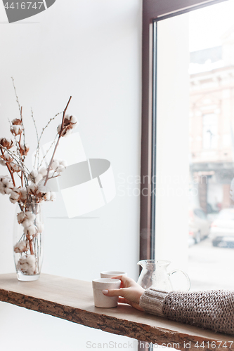 Image of Cup of coffee, branch of tree, wooden windowsill