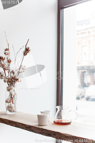 Image of Cup of coffee, branch of tree, wooden windowsill